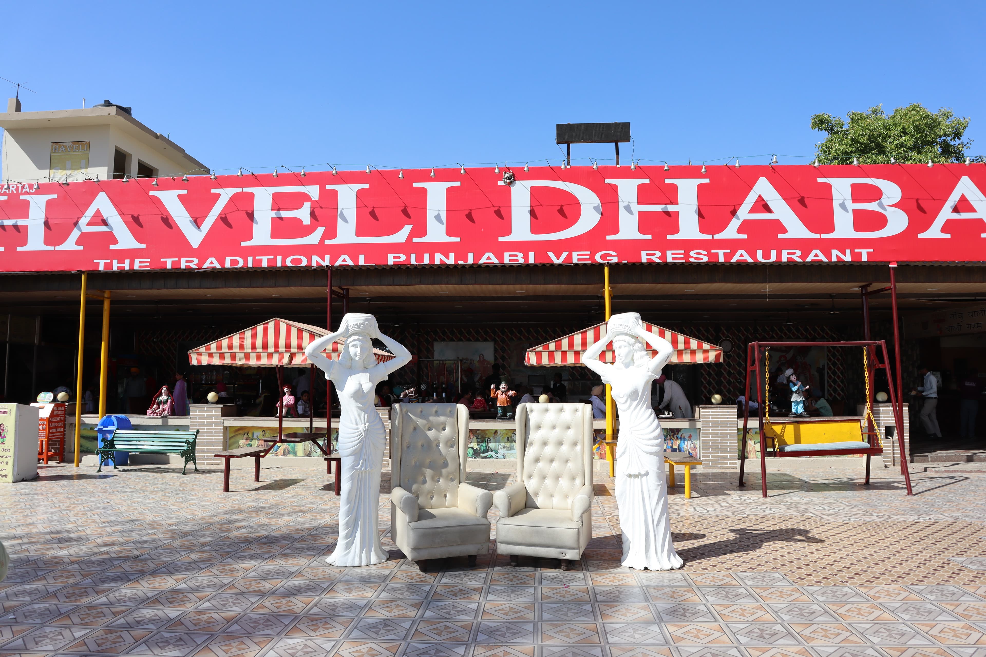 Haveli Dhaba in Maujgarh, Punjab — red banner reading 'The Traditional Punjabi Veg. Restaurant', canopy seating in the foreground.