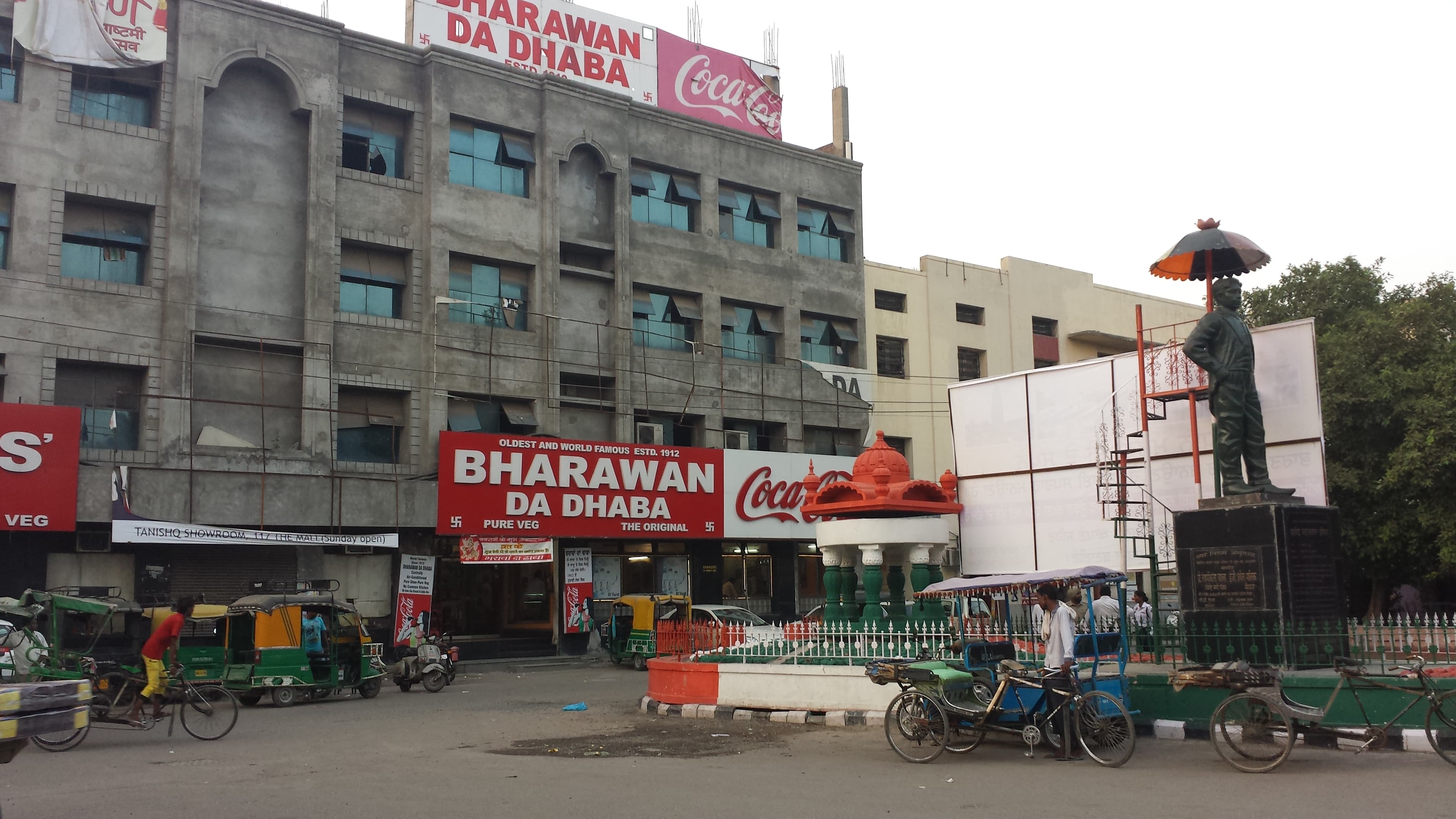 Bharawan Da Dhaba in Amritsar — established 1912, bold red and white signage on the building facade, auto-rickshaws parked outside.